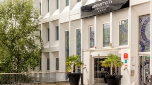 Un edificio con un letrero que dice "Appart'City Collection" y una planta grande en maceta al frente.