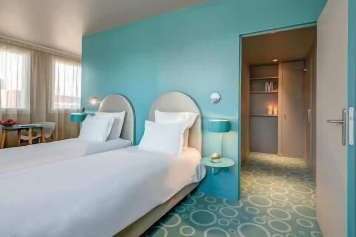 A hotel room with a bed, bedside tables, a desk, and a wardrobe.