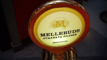 En ölfatkran med etiketten ”Melleruds UTMARKTA PILSNER”, där etiketten är gul och röd och placerad mot en röd bakgrund.