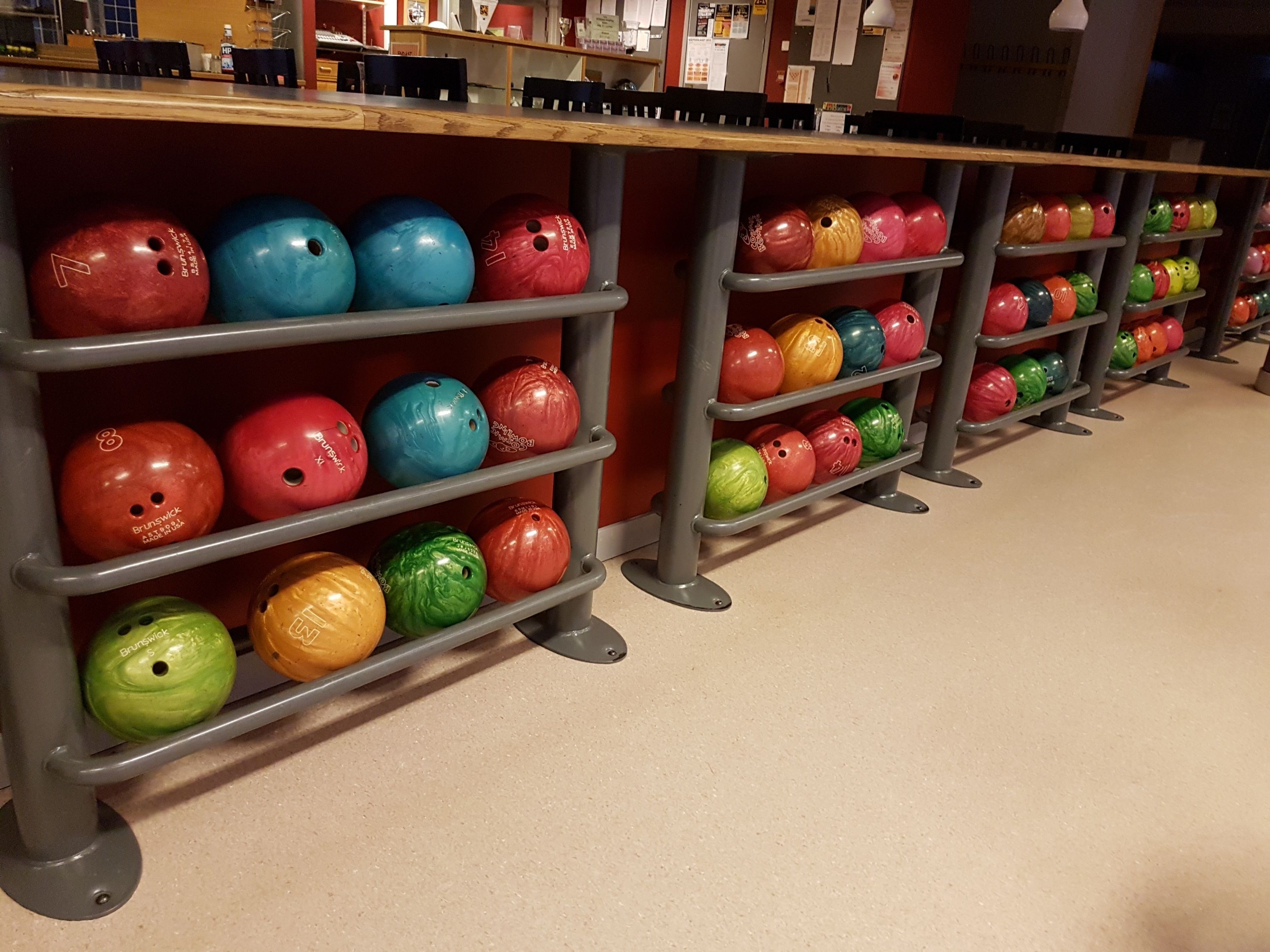 A bowling alley with multiple lanes and bowling balls organized on shelves.