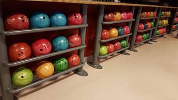 Bolera con múltiples pistas y bolas de bolos organizadas en estanterías.