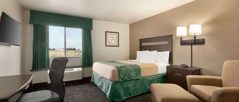 Ein Hotelzimmer mit Bett, Schreibtisch, Stuhl und Fernseher.