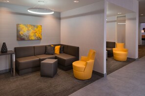 A modern lobby with a sectional sofa, a small table, and two yellow armchairs. - Residence Inn Palo Alto Menlo Park (Menlo Park)