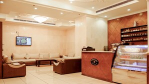 Um lobby de hotel moderno com área de estar, balcão de recepção e uma mesa com sobremesas.