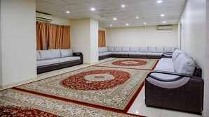 Uma sala de estar moderna com um sofá modular, um tapete estampado e uma lixeira pequena.