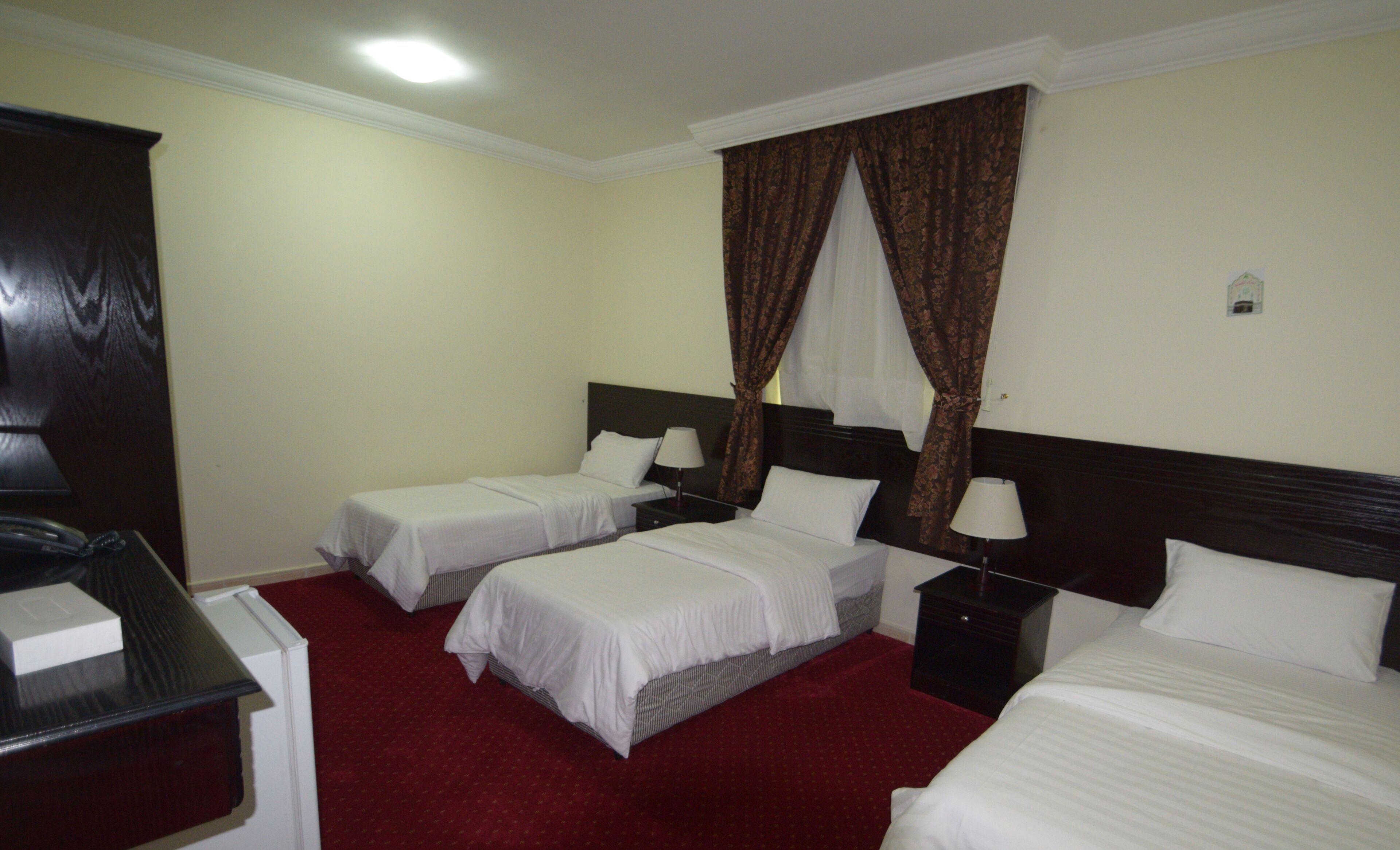 A hotel room with two single beds, a desk, and a wardrobe.