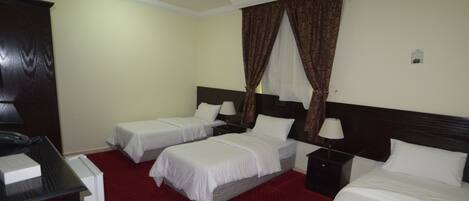A hotel room with two single beds, a desk, and a wardrobe.