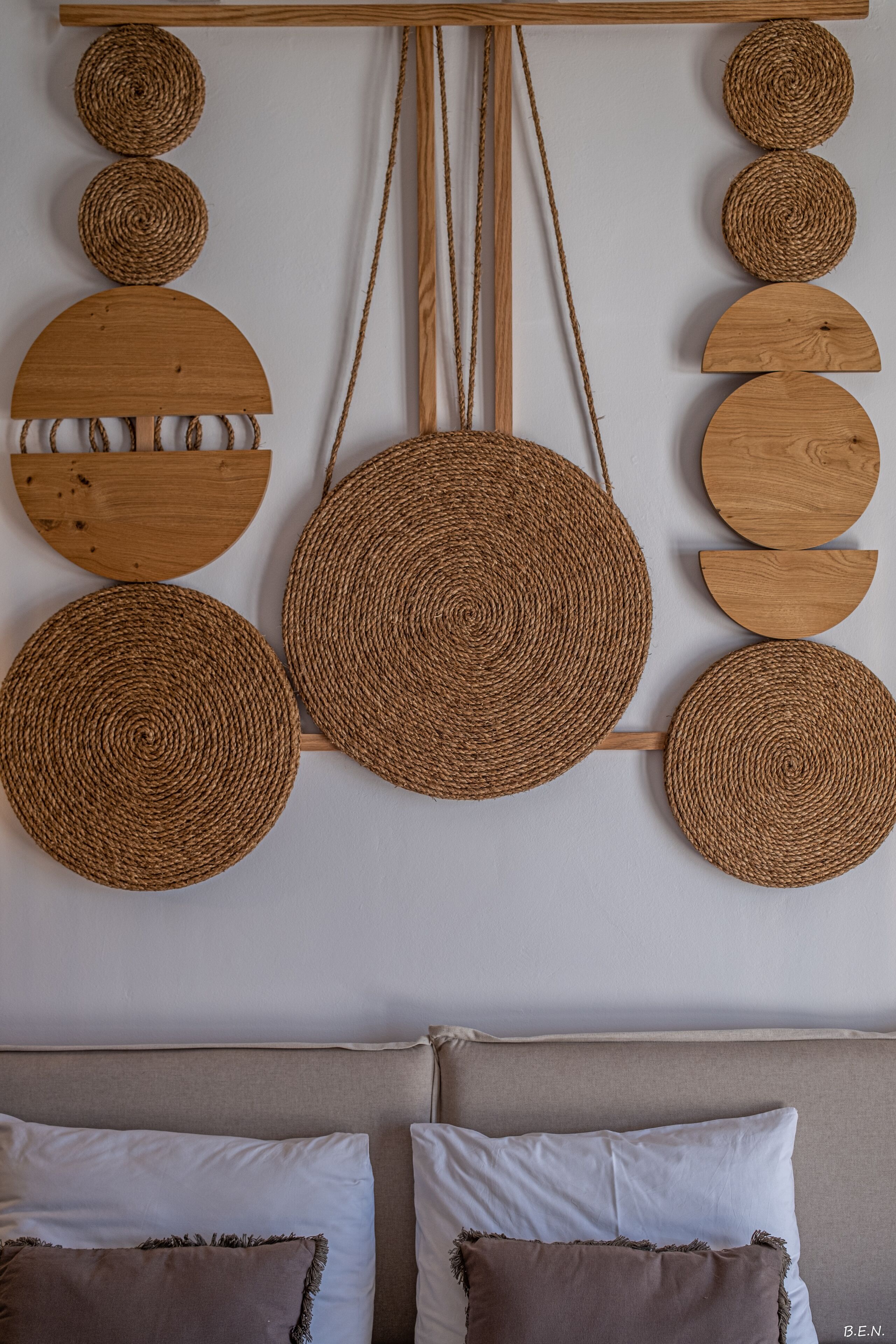 Eine Wand mit einem runden Wandbehang aus Gewebe und einem Holzregal mit verschiedenen Gegenständen.