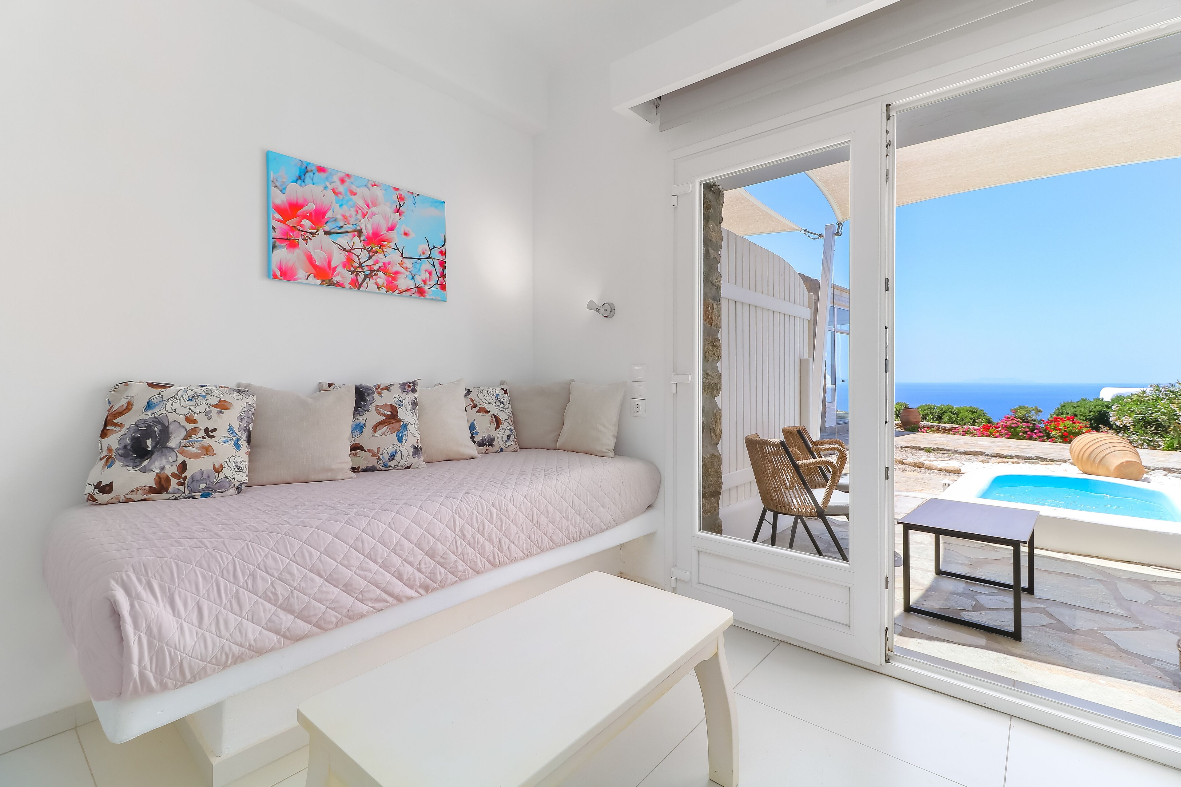 Un dormitorio con cama, una banca y vistas a una piscina exterior y jardín.