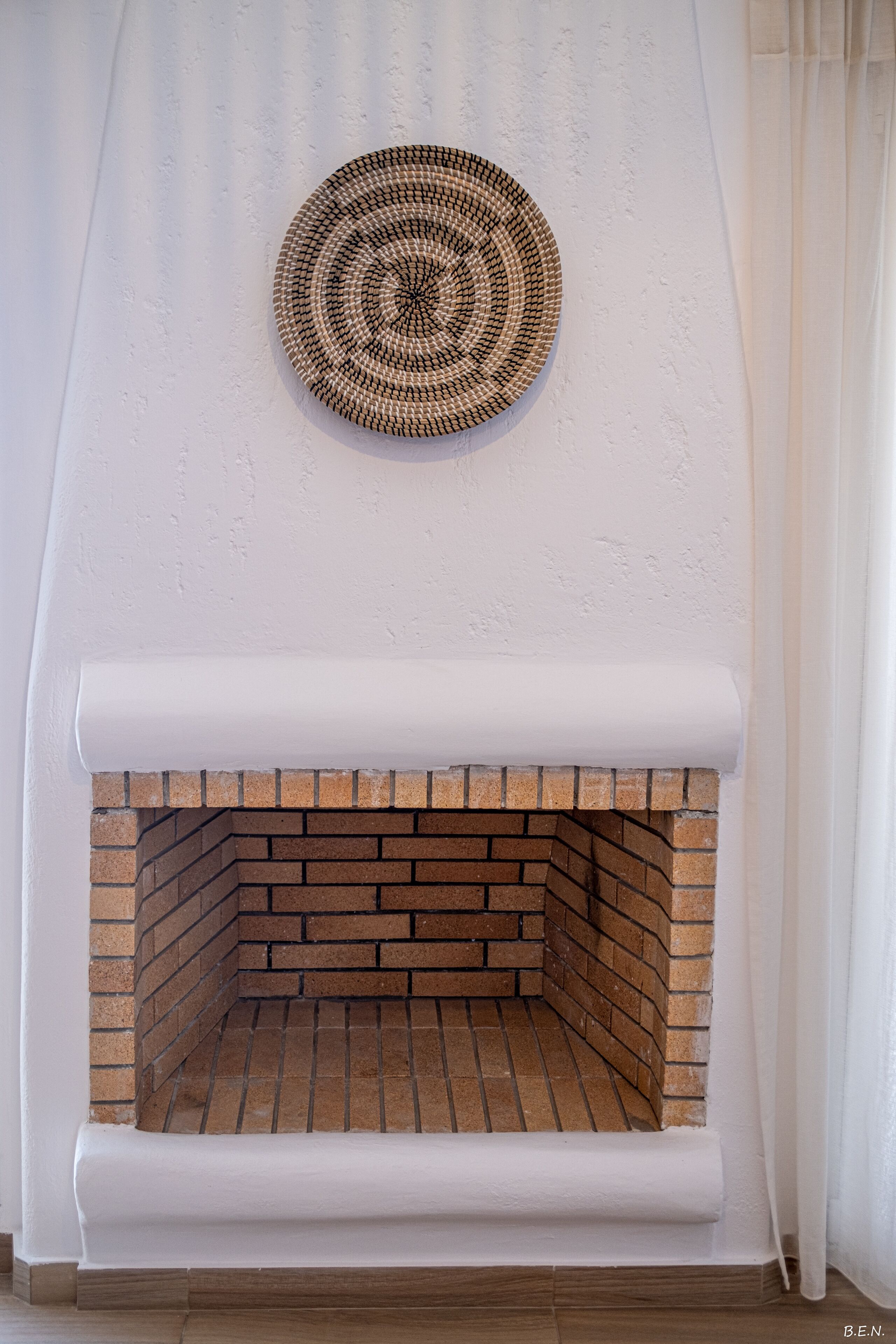 A fireplace with a brick interior and a white mantel.