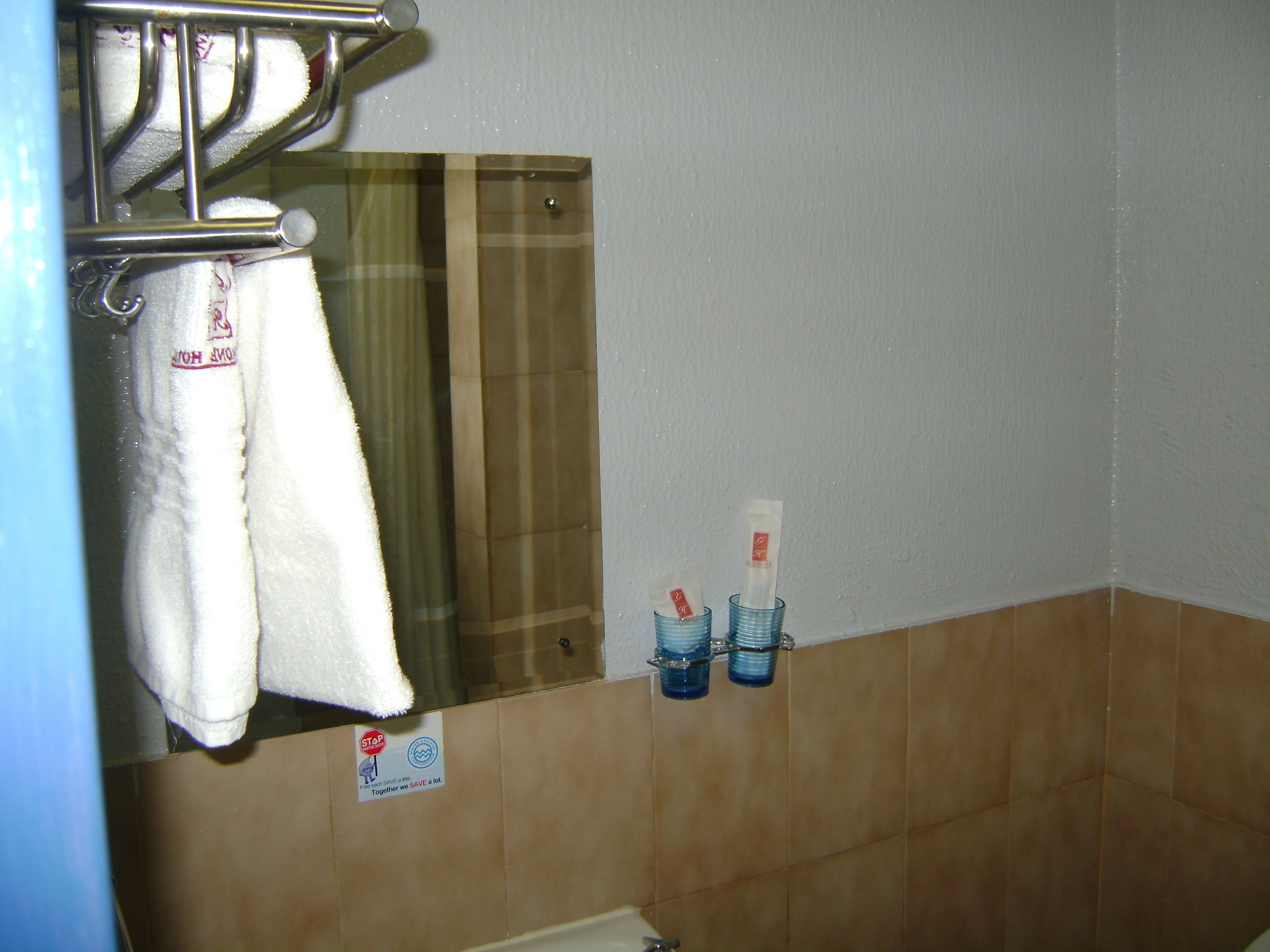 A bathroom with a towel rack, a mirror, and two bottles of hand soap on the wall.