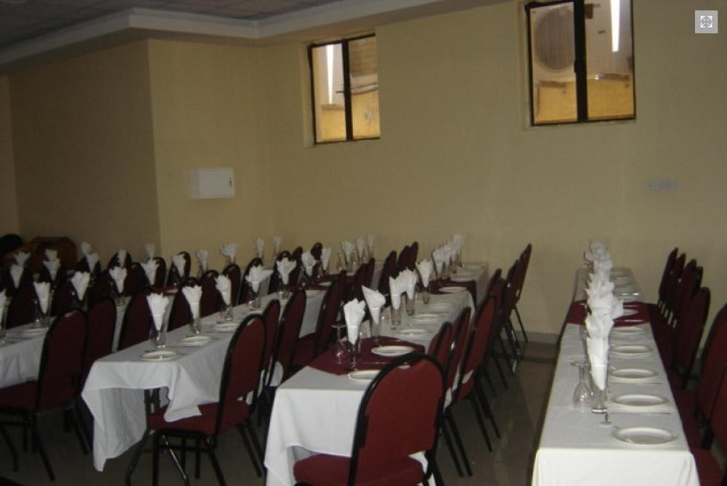 A banquet hall with multiple tables set for dining, arranged in rows.