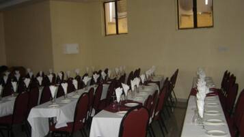 A banquet hall with multiple tables set for dining, arranged in rows.