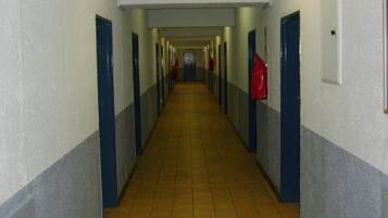 A long, narrow hallway with doors on both sides, leading to a room at the end.