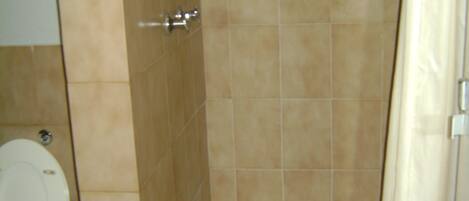 A bathroom with a shower, toilet, and a towel rack.