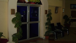 Entrada de un casino con puerta de vidrio, dos plantas en macetas y un cartel sobre la puerta.