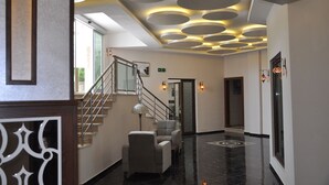 A modern hotel lobby with a staircase, seating area, and decorative ceiling lights. - Malahit Exclusive City Hotel (Fethiye)