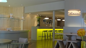 Een moderne bar met een verlichte bar, barkrukken en een hangende lamp.