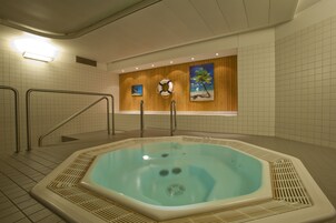 Un jacuzzi en un cuarto con piso de azulejos, paneles de madera y un cuadro de una playa.
