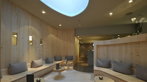 Een moderne spa-ruimte met houten wanden, zitplaatsen en kleine tafels met kaarsen.