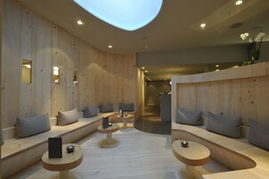 Un moderno espacio de spa con paredes de madera, asientos y pequeñas mesas con velas.