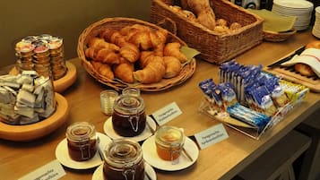 A breakfast buffet with various pastries, jams, and spreads.