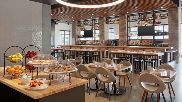 A modern dining area with a brick wall, wooden ceiling, and a variety of breakfast items on display.