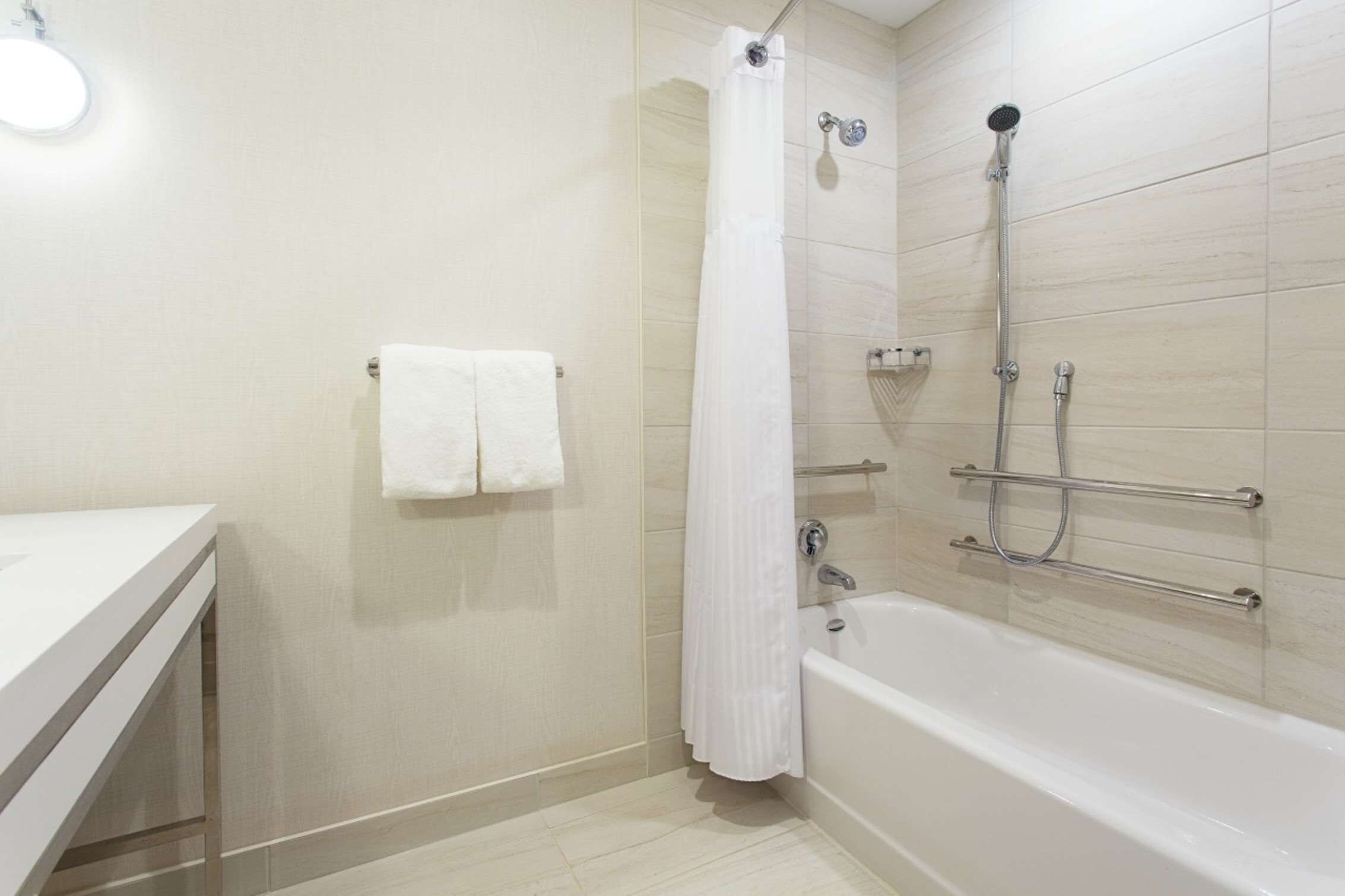 Een moderne badkamer met een bad, douche en toilet.