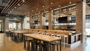 A modern bar area with multiple seating arrangements and a brick wall backdrop.