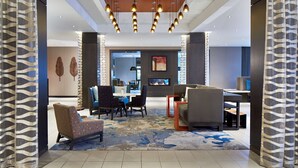 A modern lobby with a seating area, a fireplace, and a television screen.