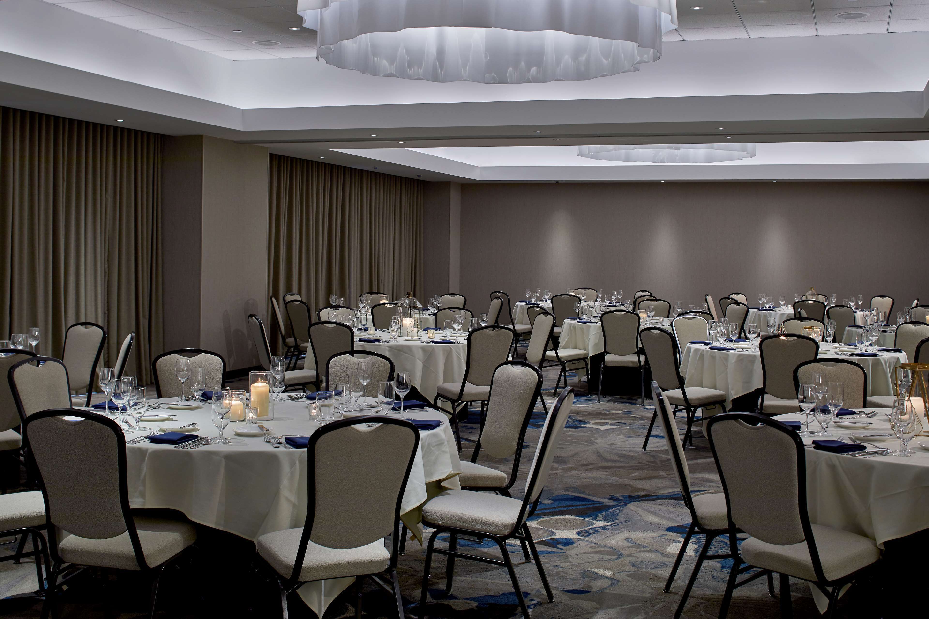 A banquet hall with round tables, chairs, and dining tables set for a formal event.