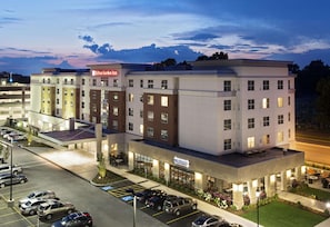 A multi-story hotel with a parking lot, a visible restaurant, and a clear sky.