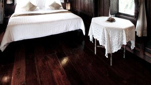 A wooden room with a bed, a small table, and a window with curtains. - Dhabkwan Resort (Nonthaburi)