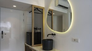 A modern bathroom with a white door, a black sink, and a round mirror with a lighted frame. - Stella Maria (Hersonissos)