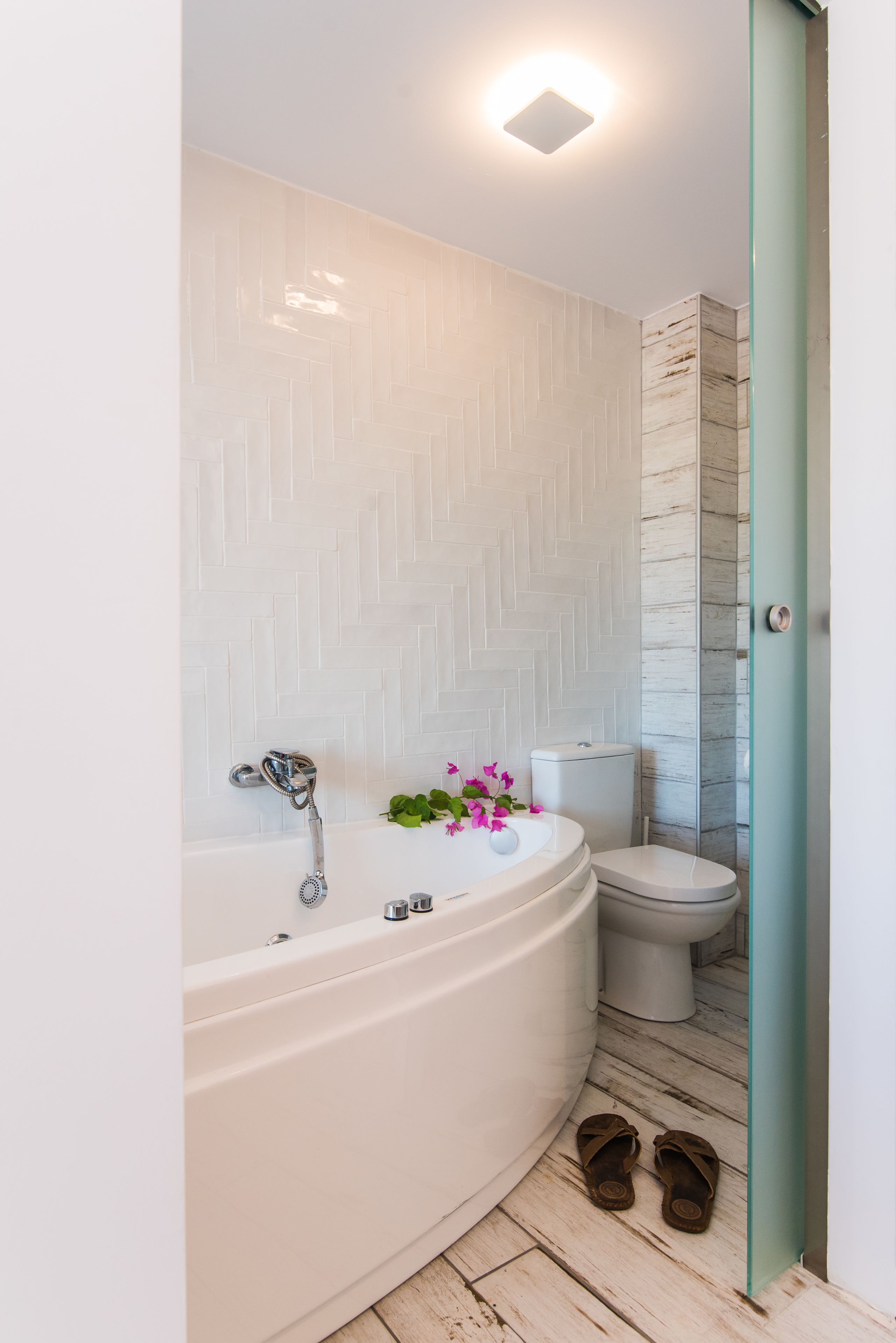 A bathroom with a white bathtub, a toilet, and a shower area.