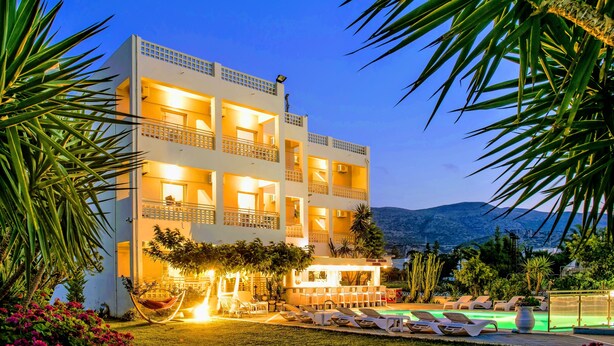 A multi-story hotel with balconies, a pool area, and a view of the mountains. - Stella Maria (Hersonissos)