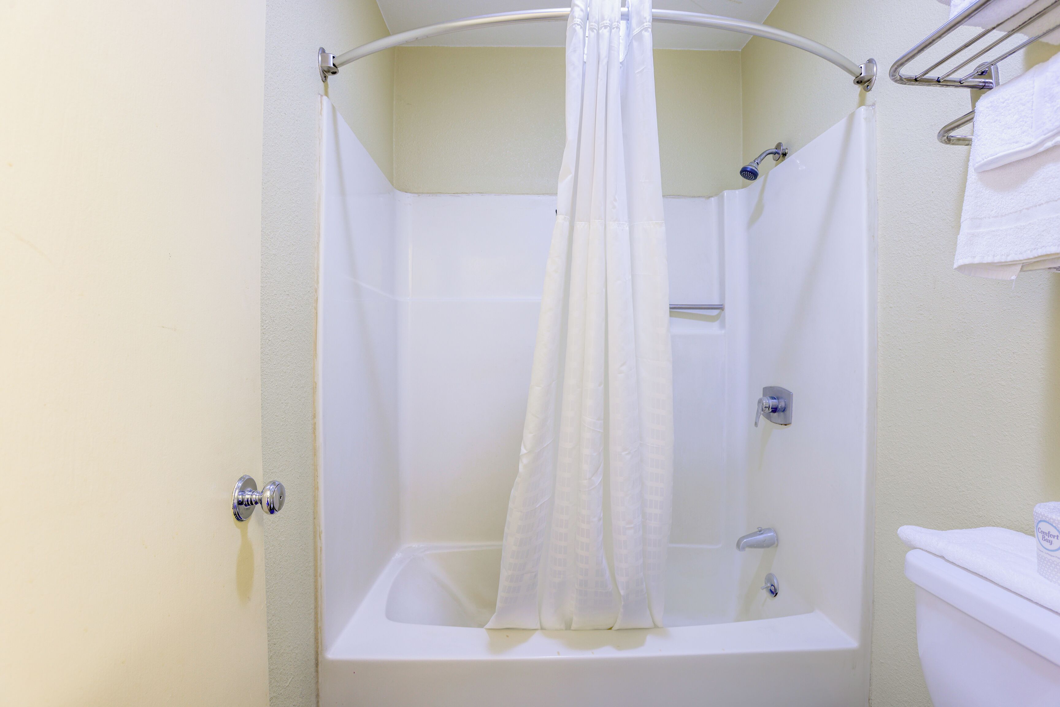 A bathroom with a shower, toilet, and towel rack.