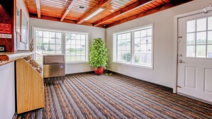 A room with wooden beams on the ceiling, large windows, a potted plant, and a refrigerator. - Budget Inn By OYO Natural Bridge I-81 (Natural Bridge)