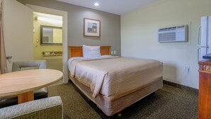 A hotel room with a bed, a bedside table, a chair, a small table, a mirror, and a picture on the wall. - Budget Inn By OYO Natural Bridge I-81 (Natural Bridge)