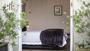 A bedroom with a bed, a bedside lamp, and a framed picture on the wall. - Majestic Mansions - Apartments at St Clair (Dunedin)