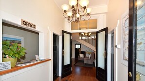 A reception area with a sign reading "OFFICE," a potted plant, and a staircase leading to another level. - Majestic Mansions - Apartments at St Clair (Dunedin)