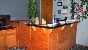 A reception desk with a wooden finish, a clock, and an American flag.
