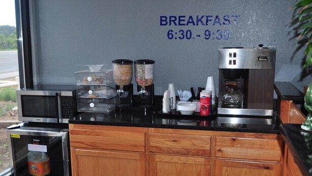 A breakfast area with a microwave, coffee machine, and food dispensers.