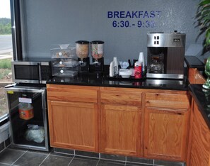 A breakfast area with a microwave, coffee machine, and food dispensers. - Bestway Inn (Ruidoso Downs)