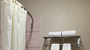 A bathroom with a bathtub, toilet, and a towel rack with two towels.