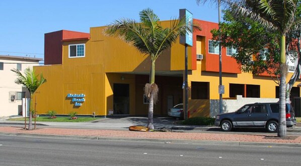 A yellow building with a sign reading "Hotel Beach Inn".