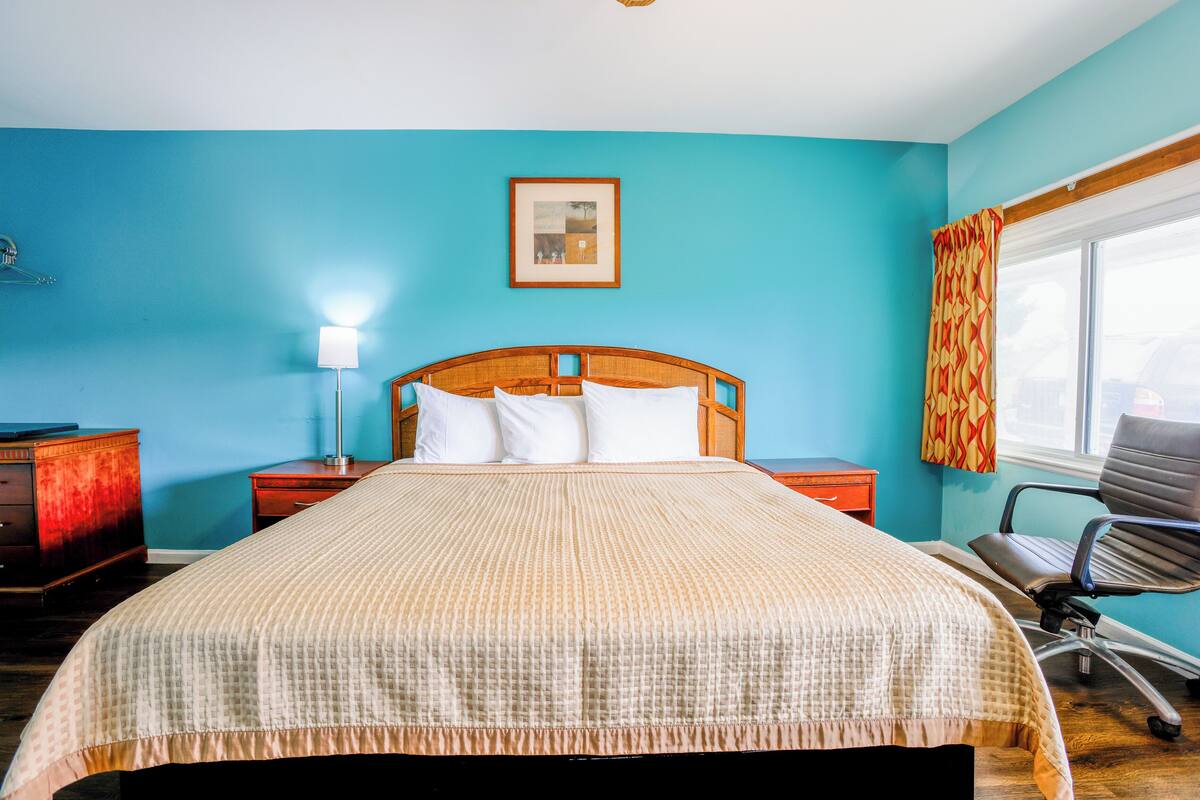 A bedroom with a bed, nightstands, a desk, and a chair.