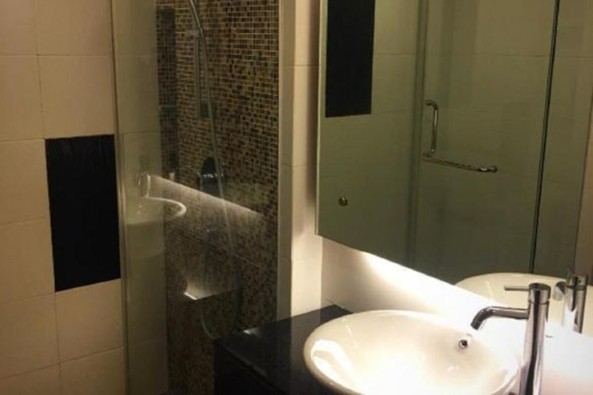 Un baño moderno con ducha acristalada, lavamanos blanco y espejo.