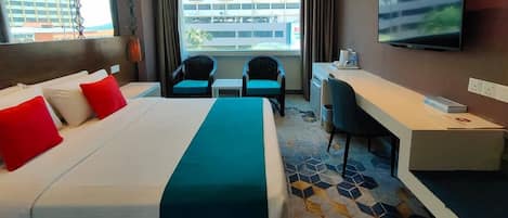 Habitación de hotel con una cama grande, dos sillas, un escritorio y un televisor.