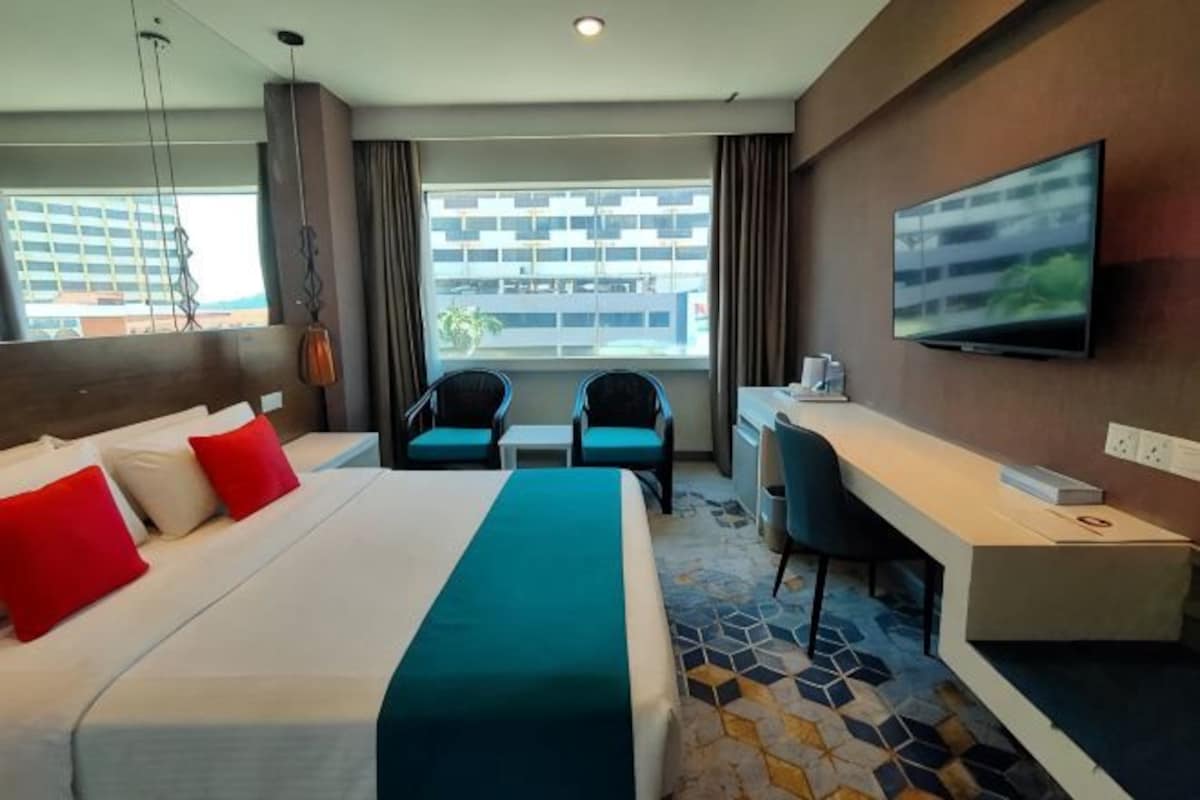 Una habitación de hotel con cama, escritorio, televisión y vistas a la ciudad.